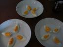 Gekookte eieren in vieren snijden en in ieder diep bord vier partjes ei leggen.